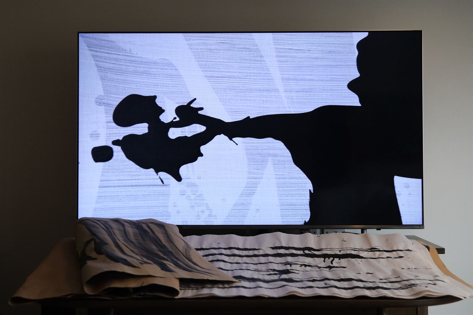 A screen playing an ink animation, a calligraphy scroll draped beneath it