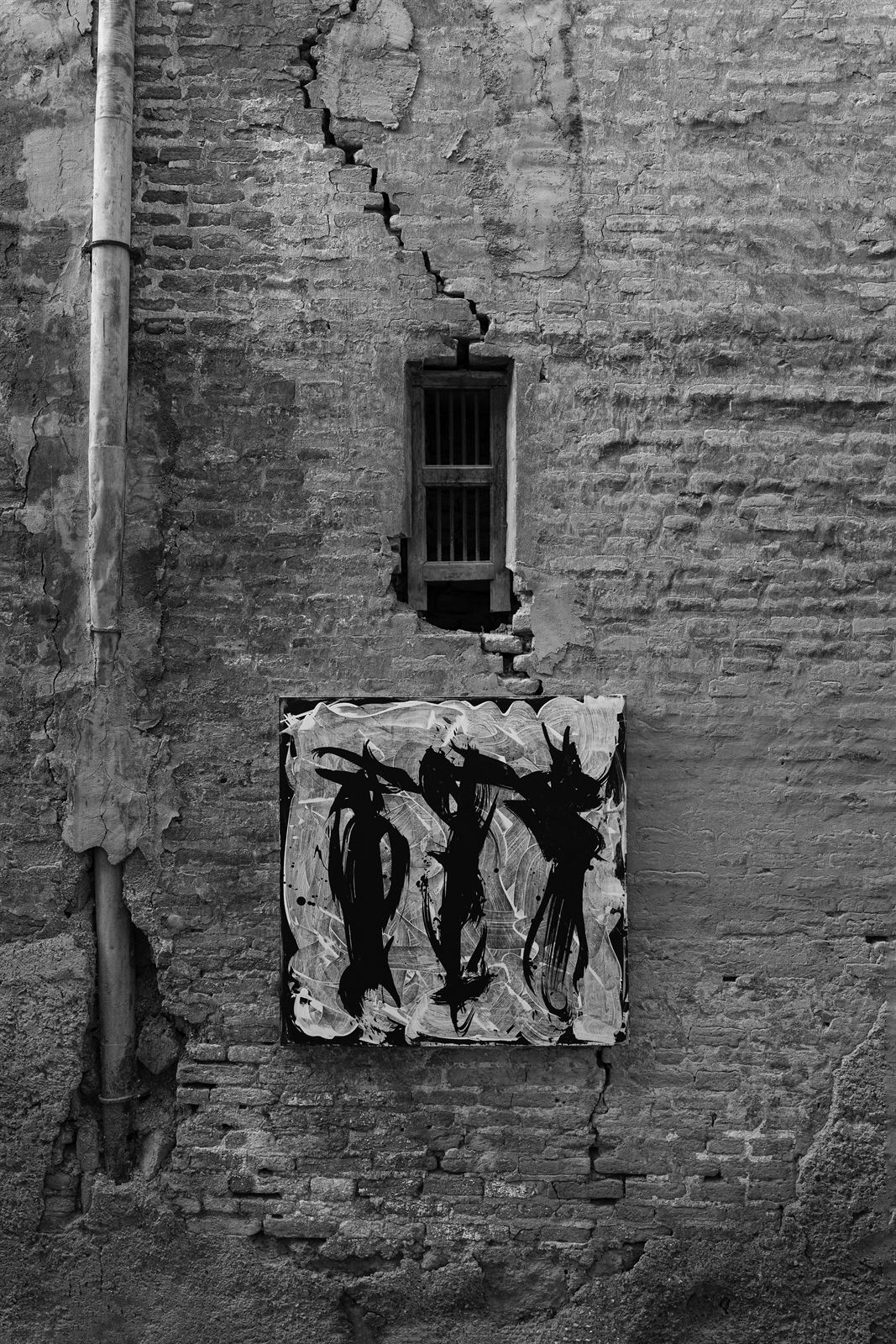 A canvas hung beneath a barred window, a crack running up the wall