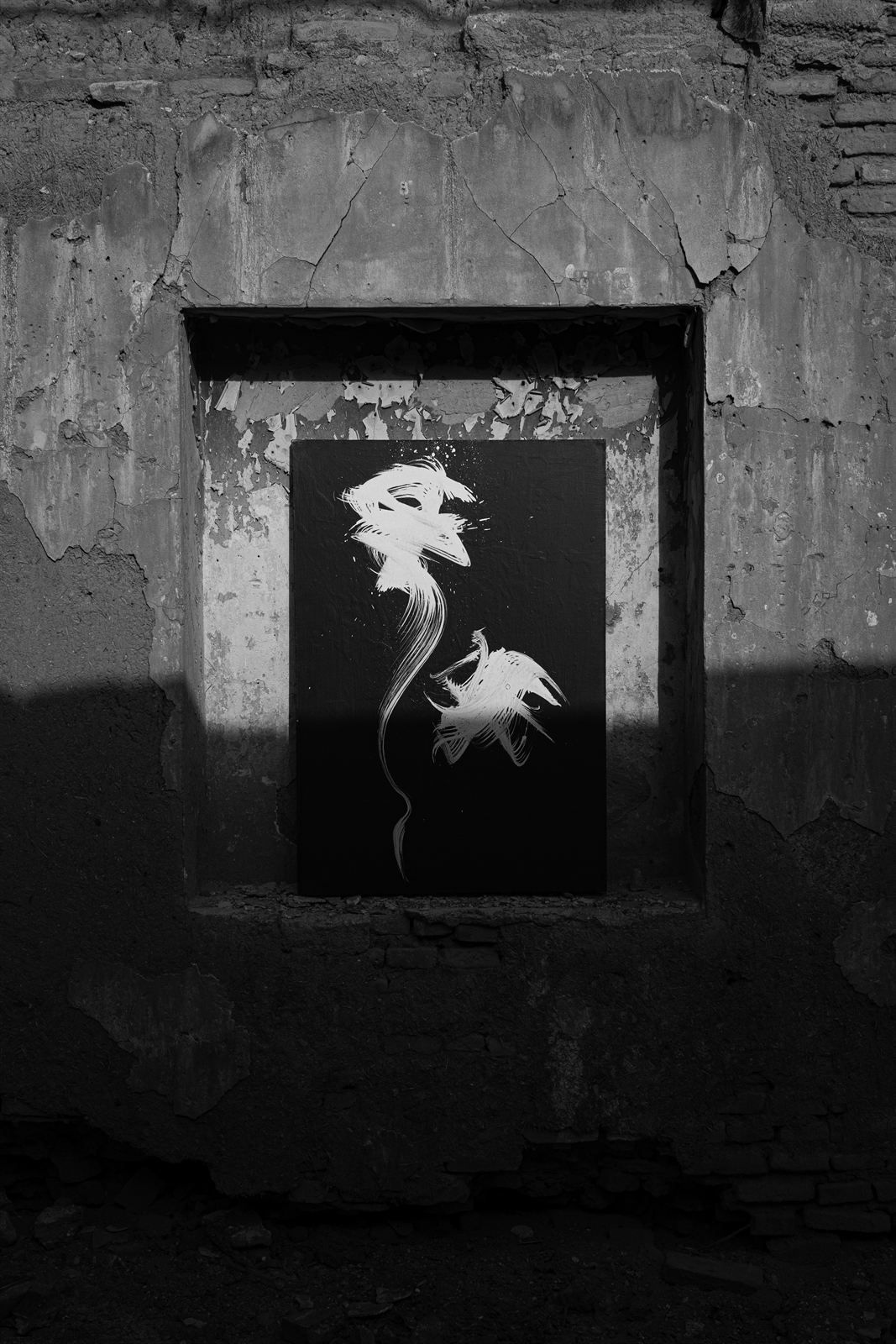 A canvas set in a ruined window recess, half in hard sunlight