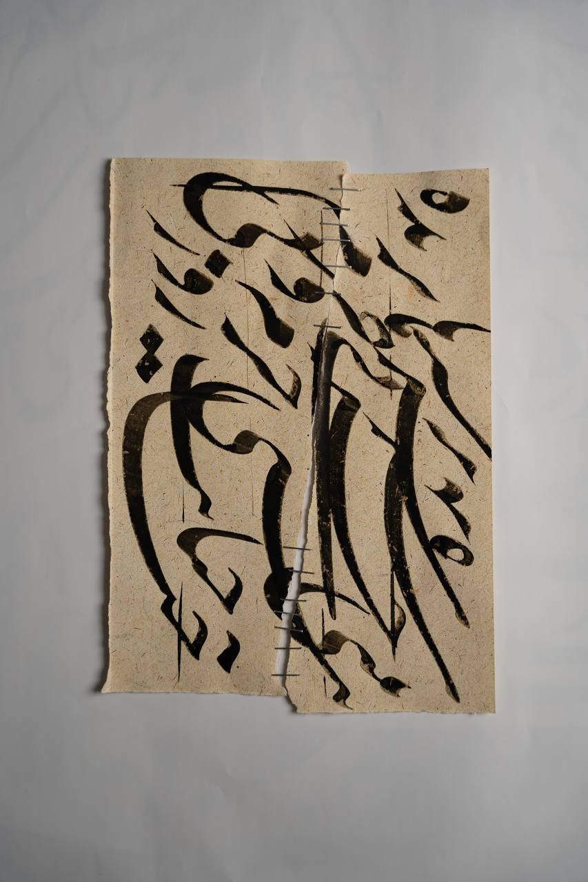 Two torn halves of a calligraphy sheet stitched together with staples